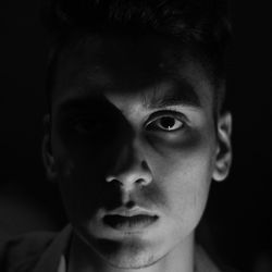 Close-up portrait of young man against black background