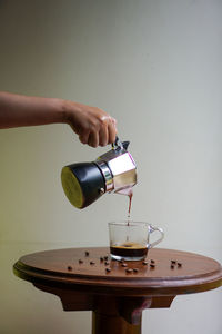 Midsection of person pouring coffee in cup