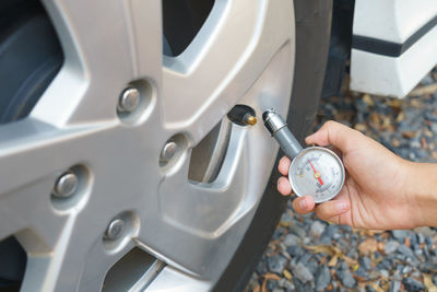 Close-up of hand checking tire air pressure of car