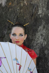 Portrait of young woman standing against wall