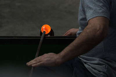 Midsection of man making glass in factory
