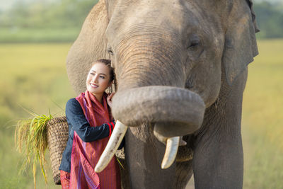 Smiling woman standing by elephant