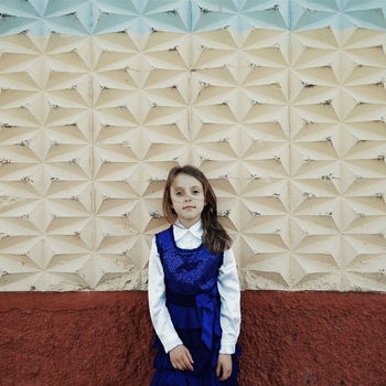 FULL LENGTH OF YOUNG WOMAN STANDING AGAINST WALL IN ROOM