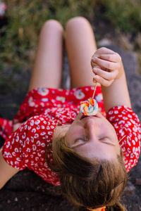 High angle view of woman eating lollipop while sitting outdoors