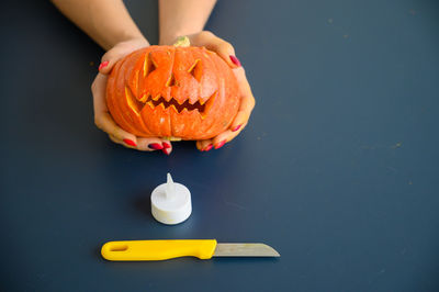 Midsection of person holding pumpkin against black background