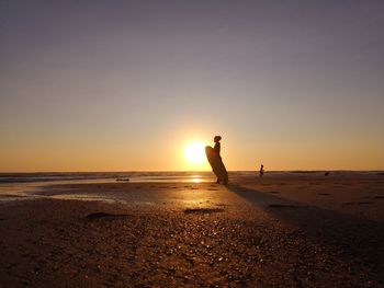 Silhouette man on beach against sky during sunset