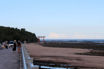 People walking on beach against sky