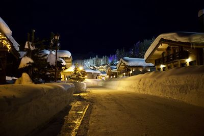 Road by illuminated buildings in city at night