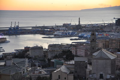 High angle view of sea by buildings against sky during sunset