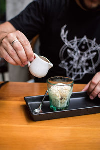 Midsection of man holding ice cream on table