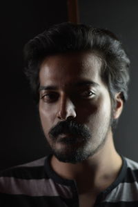 Close-up portrait of young man against black background