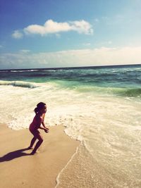 Full length of boy playing on beach against sky