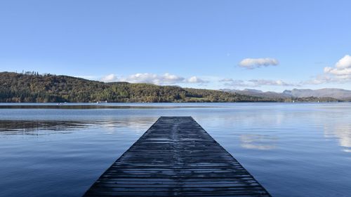 Pier over lake against blue sky