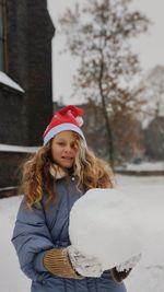 Portrait of smiling young woman sitting on snow