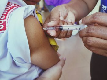 Cropped hands of doctor vaccinating child in hospital