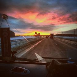 Road by sea against sky during sunset