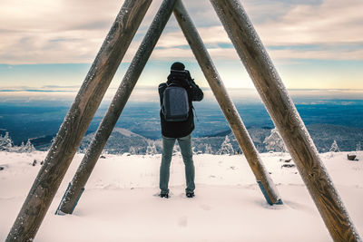 Rear view of man standing on snow covered land during winter