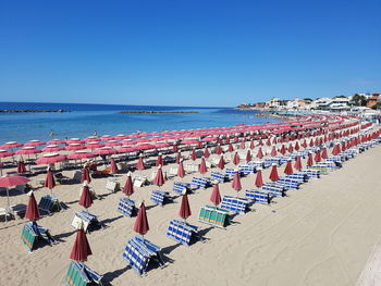 Chairs on beach against clear blue sky