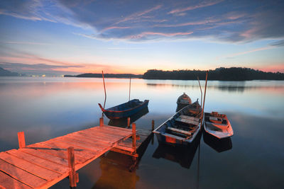 Boats moored in calm lake against sky