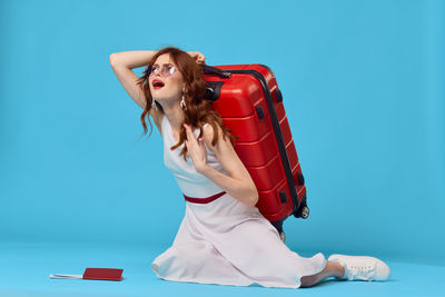 Young woman with umbrella against blue background