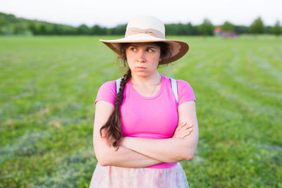 Portrait of woman wearing hat standing on field