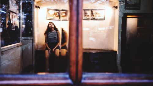 Woman standing by window at illuminated store