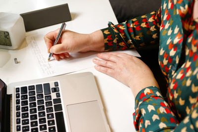 Midsection of woman using laptop on table