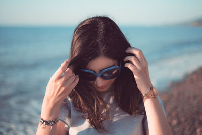 Portrait of young woman wearing sunglasses at beach