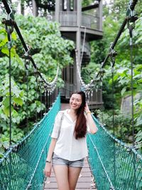 Portrait of beautiful woman standing on footbridge