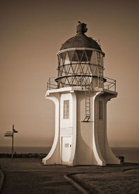 View of lighthouse by sea against clear sky