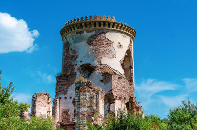 Ancient ruined stone tower in bushes. blue sky background.