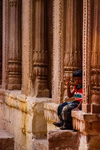 Woman sitting on historical building