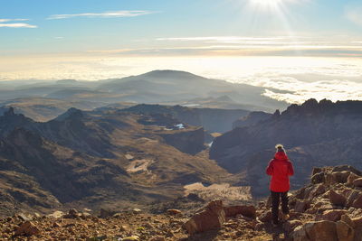 Rear view of woman standing on mountain against sky