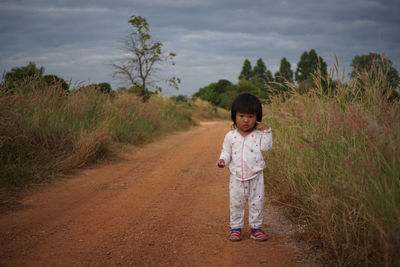 Portrait of cute girl standing on dirt road