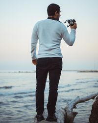 Rear view of man photographing at beach
