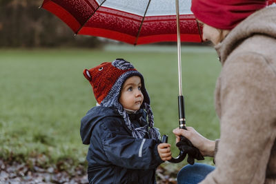 Mother and daughter with umbrella on field during rainy season