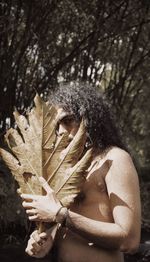 Close-up of woman with leaves on tree in forest