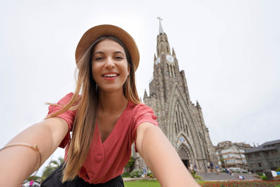 Portrait of young woman standing against sky