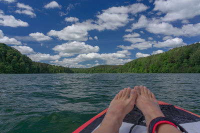 Low section of man on lake against sky