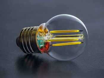 Led filament light bulb with an amber-colored glass shell on the background of dark background.