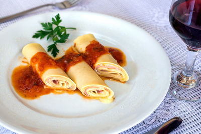 Close-up of cannelloni pasta with tomato sauce and red wine on table