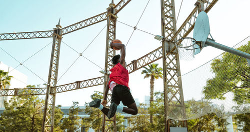 Low angle view of man standing on rope against sky