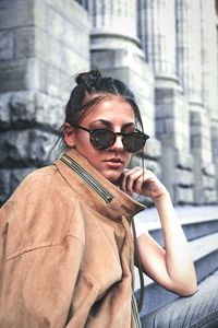 Portrait of woman holding sunglasses in city