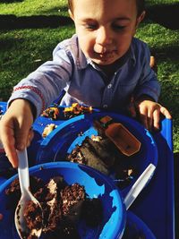 High angle view of boy eating chocolate cake in back yard