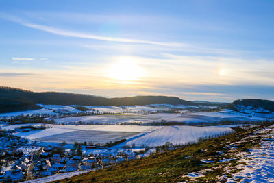 Scenic view of snow covered field against sky during sunset