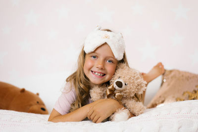 Cute baby girl lies on the bed and hugs her favorite toy and smiles