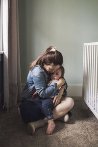 Portrait of mother hugging toddler daughter in window light