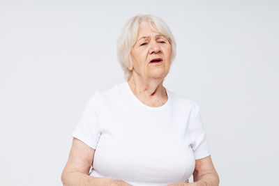 Portrait of young woman standing against white background