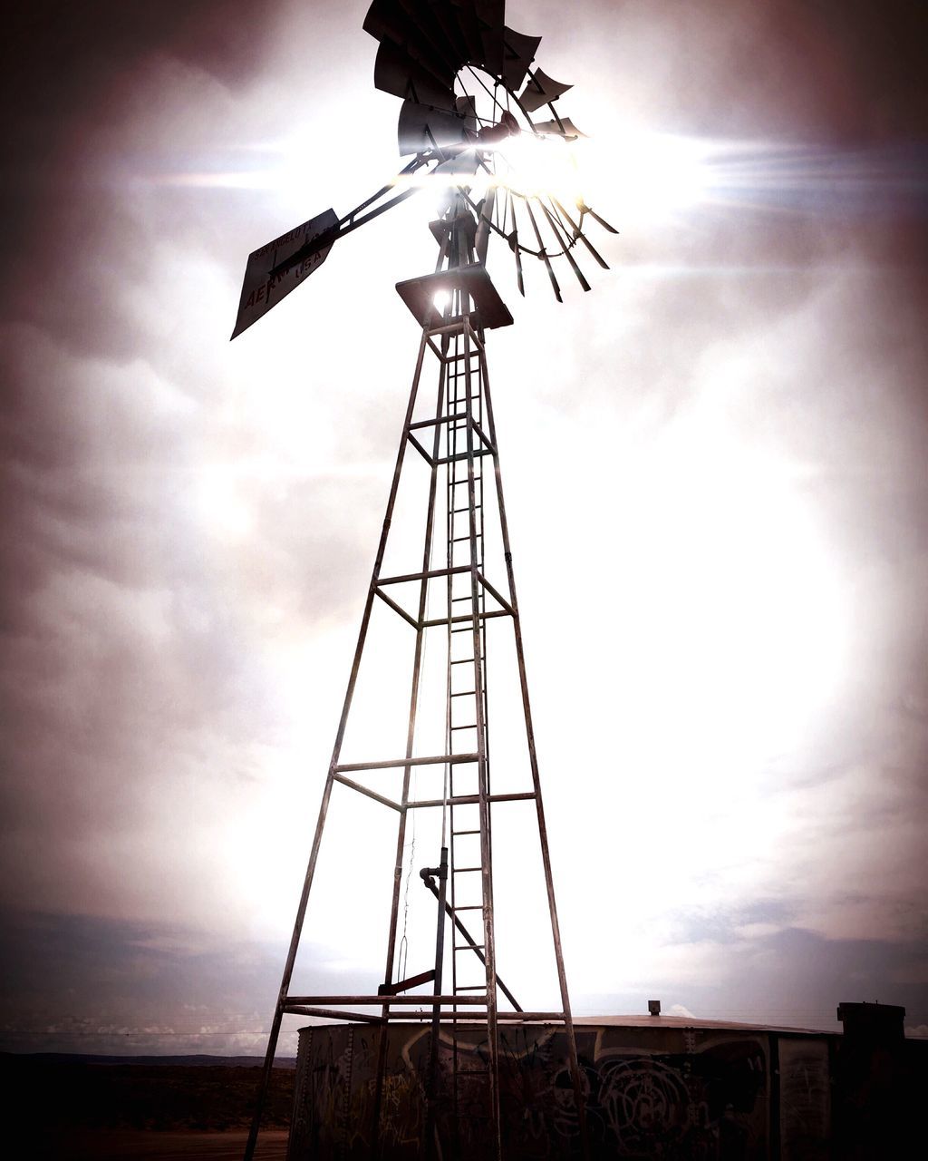 ELECTRICITY PYLON WITH WINDMILL IN BACKGROUND