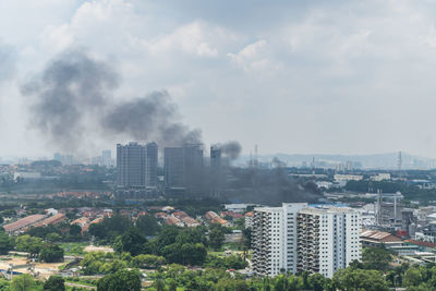 Smoke amidst cityscape against sky